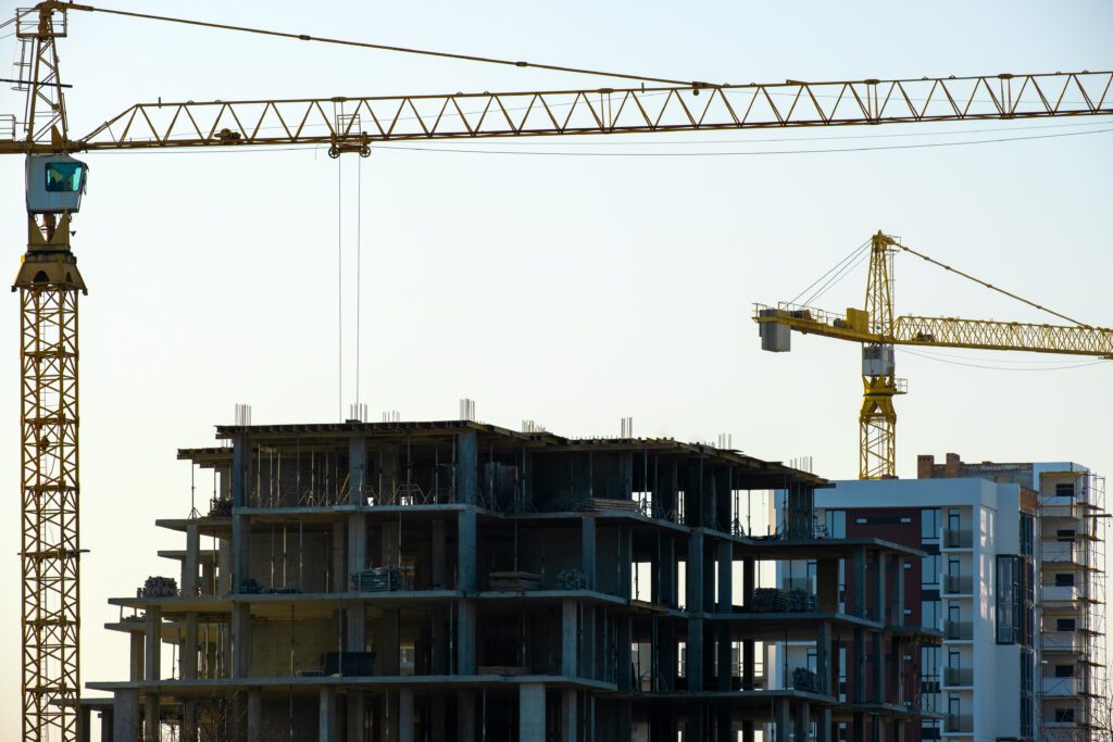 Aerial view of tower cranes and high residential apartment buildings under construction. Real estate development.