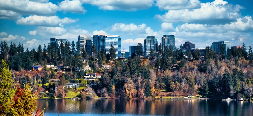 Scenic view of Bellevue with skyscrapers hidden behind trees across Lake Washington A scenic view of Bellevue with skyscrapers hidden behind trees across Lake Washington