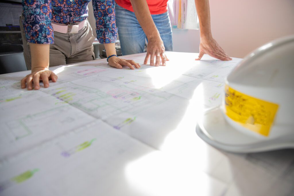 Two colleagues analyze a technical drawing while in the office. Two colleagues analyze a technical drawing while in the office